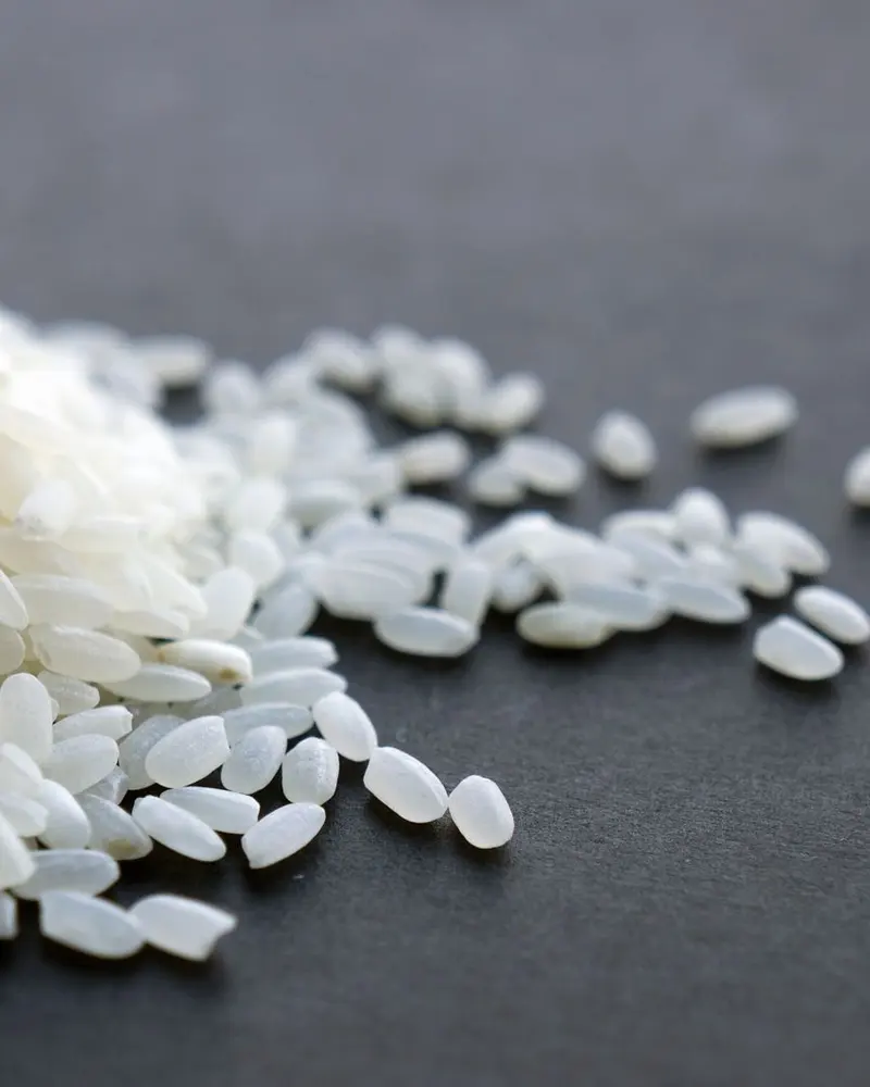 A heap of white rice on a dark surface