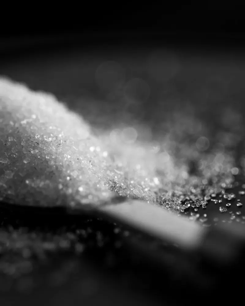 A spoonful of white sugar on a dark background