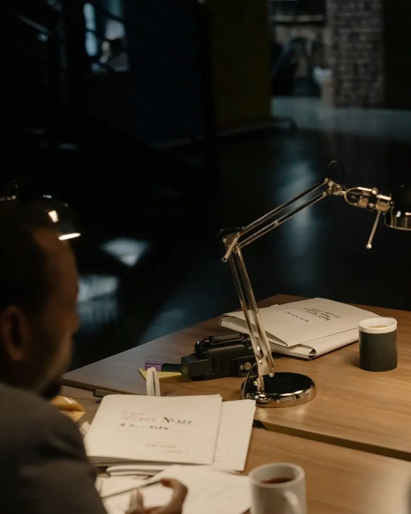 Two men in a business conversation at a desk under a desk lamp